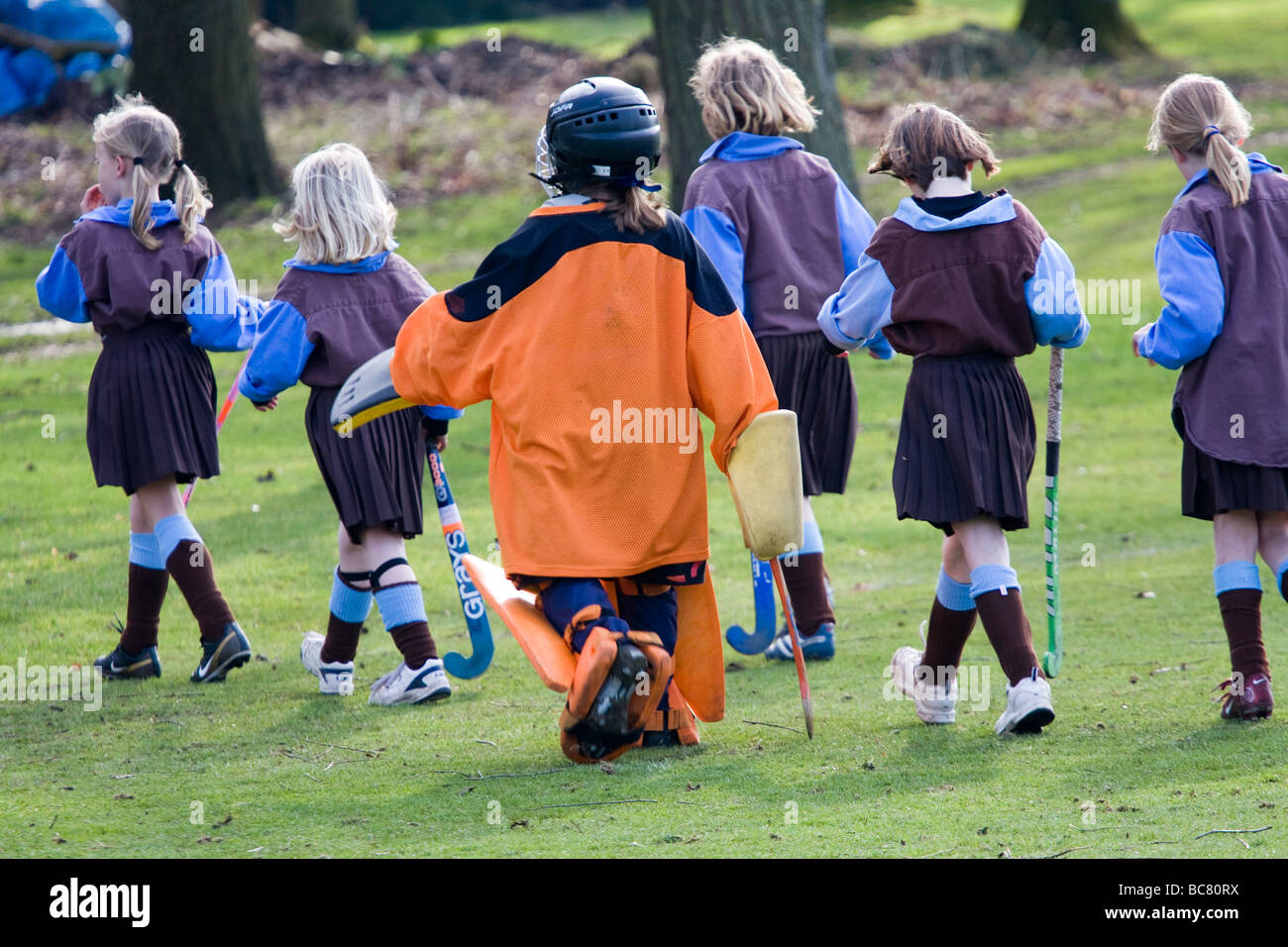 Young girl field hockey players of Brandeston prep school team leave the pitch with the goalie engulfed in her kit Stock Photo