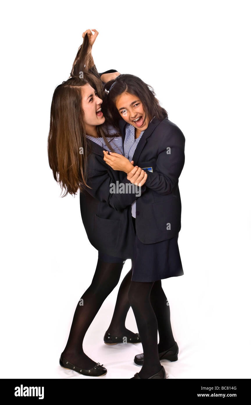 Vertical full length portrait of two school girls fighting against a white background Stock Photo