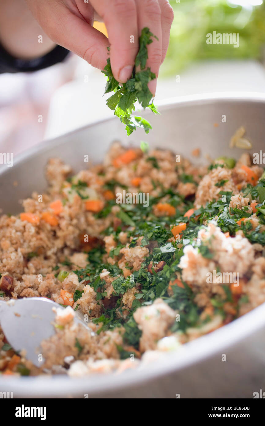 Sprinkling parsley into bread stuffing - Stock Photo