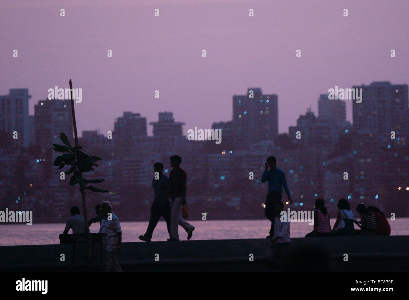 People walk along the Marine Drive at dusk in Mumbai in India Stock Photo