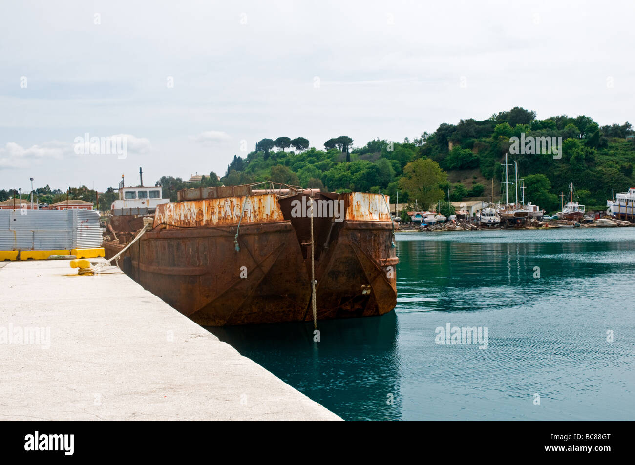 A rust covered sea going barge moored alongside a jetty, Corfu Stock Photo
