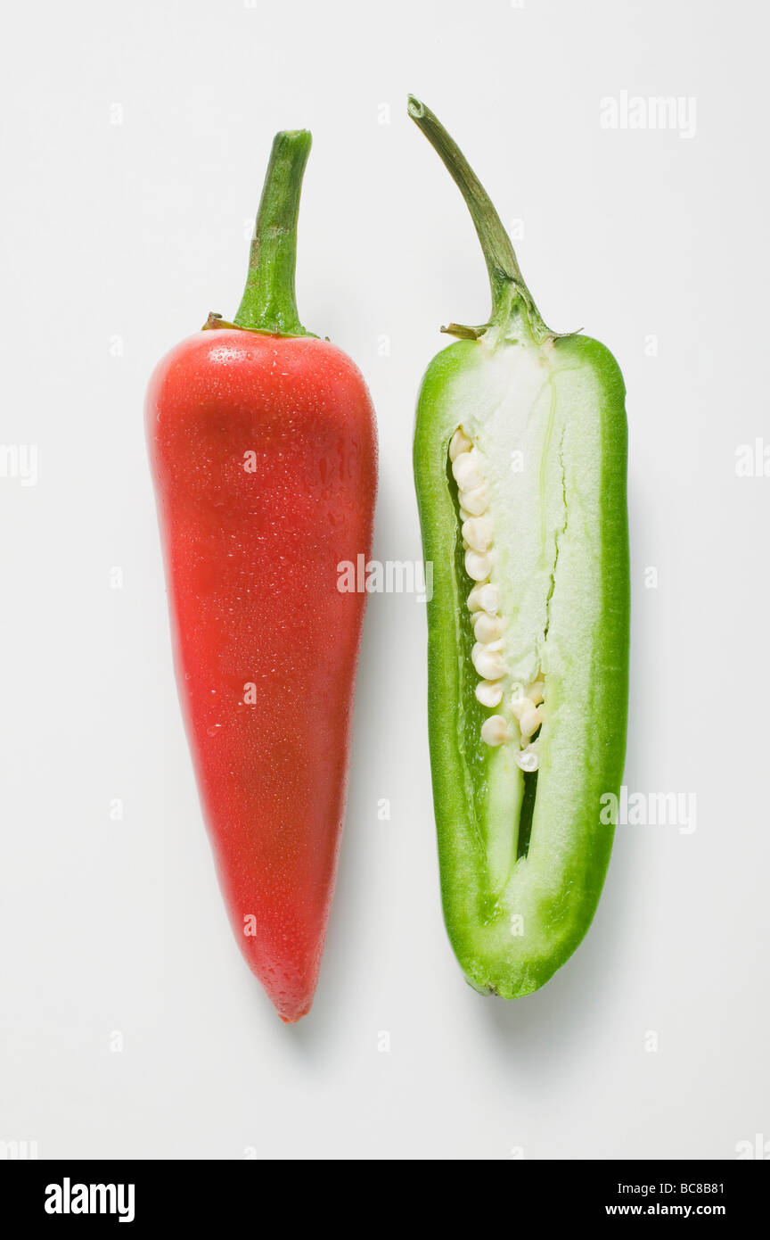 Whole red chilli and half a green chilli - Stock Photo