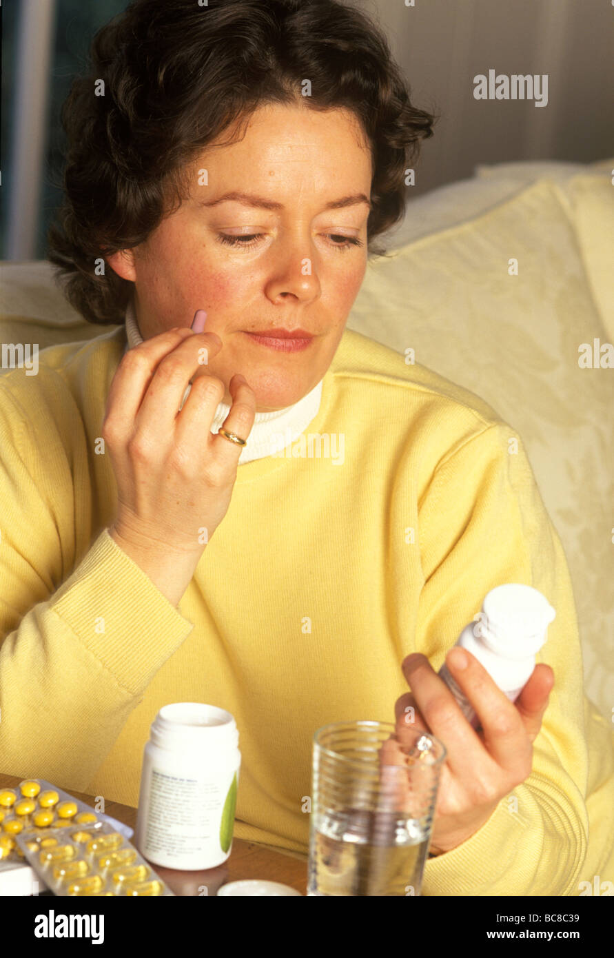 woman with a mixture of pills deciding what to take Stock Photo