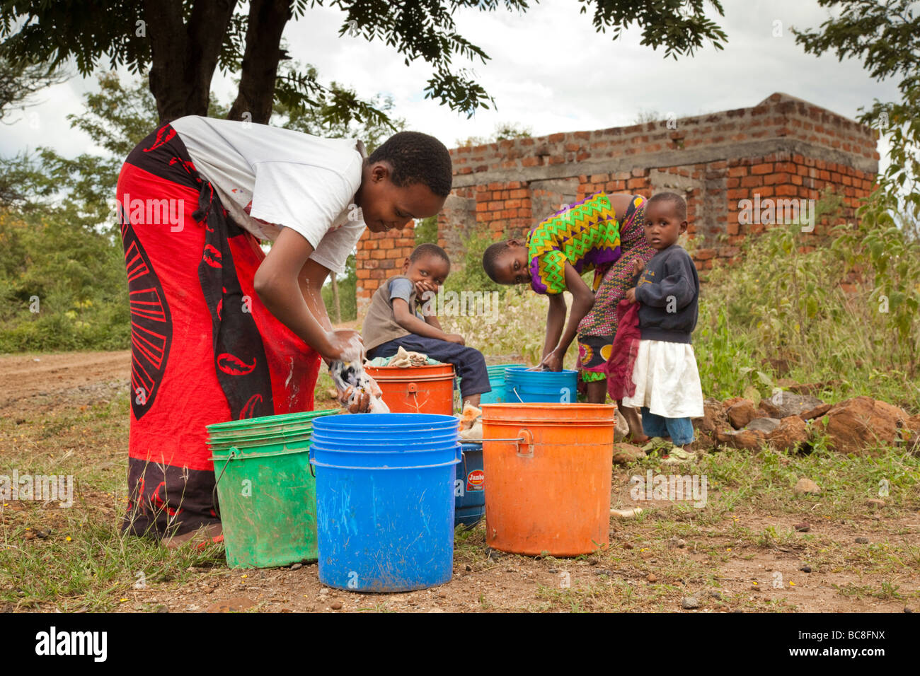 African girls washing laundry by hand in brightly coloured buckets