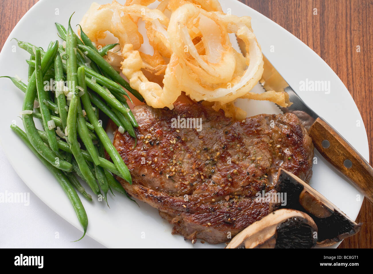Ribeye steak with green beans and deepfried onion rings Stock Photo