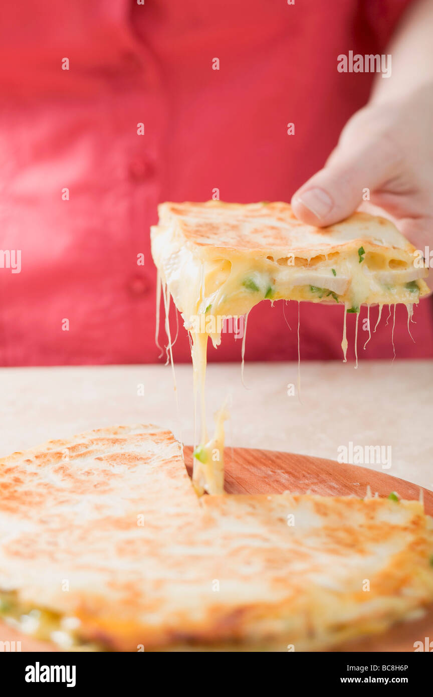 Hand taking piece of quesadilla from wooden board - Stock Photo