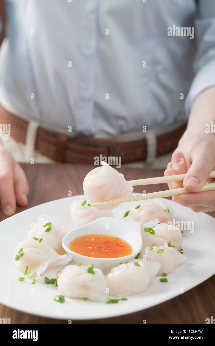 Woman eating dim sum with chilli sauce Stock Photo Alamy