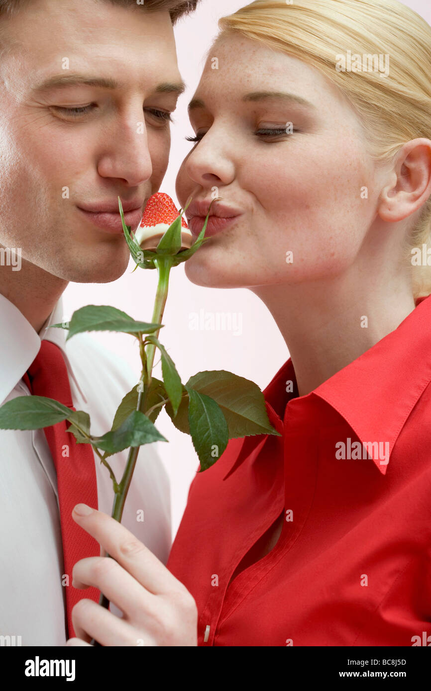 Couple kissing chocolatedipped strawberry on rose stalk Stock Photo