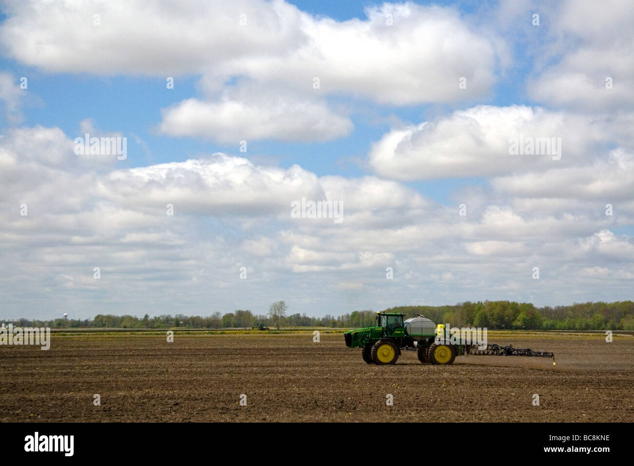 Tractor spraying herbicide on tilled crop soil in Lapeer County Michigan USA Stock Photo