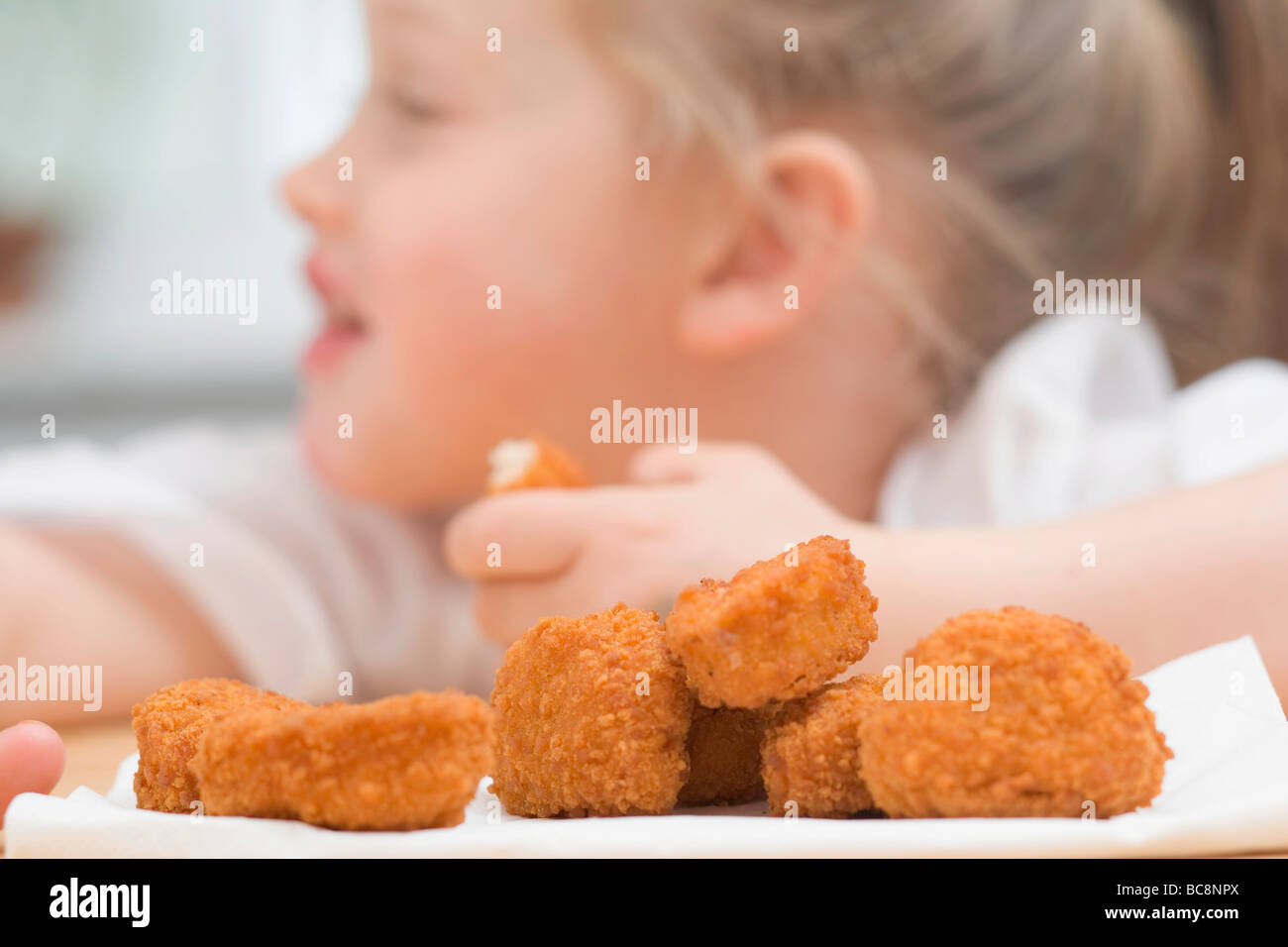 Little girl eating chicken nuggets Stock Photo Alamy