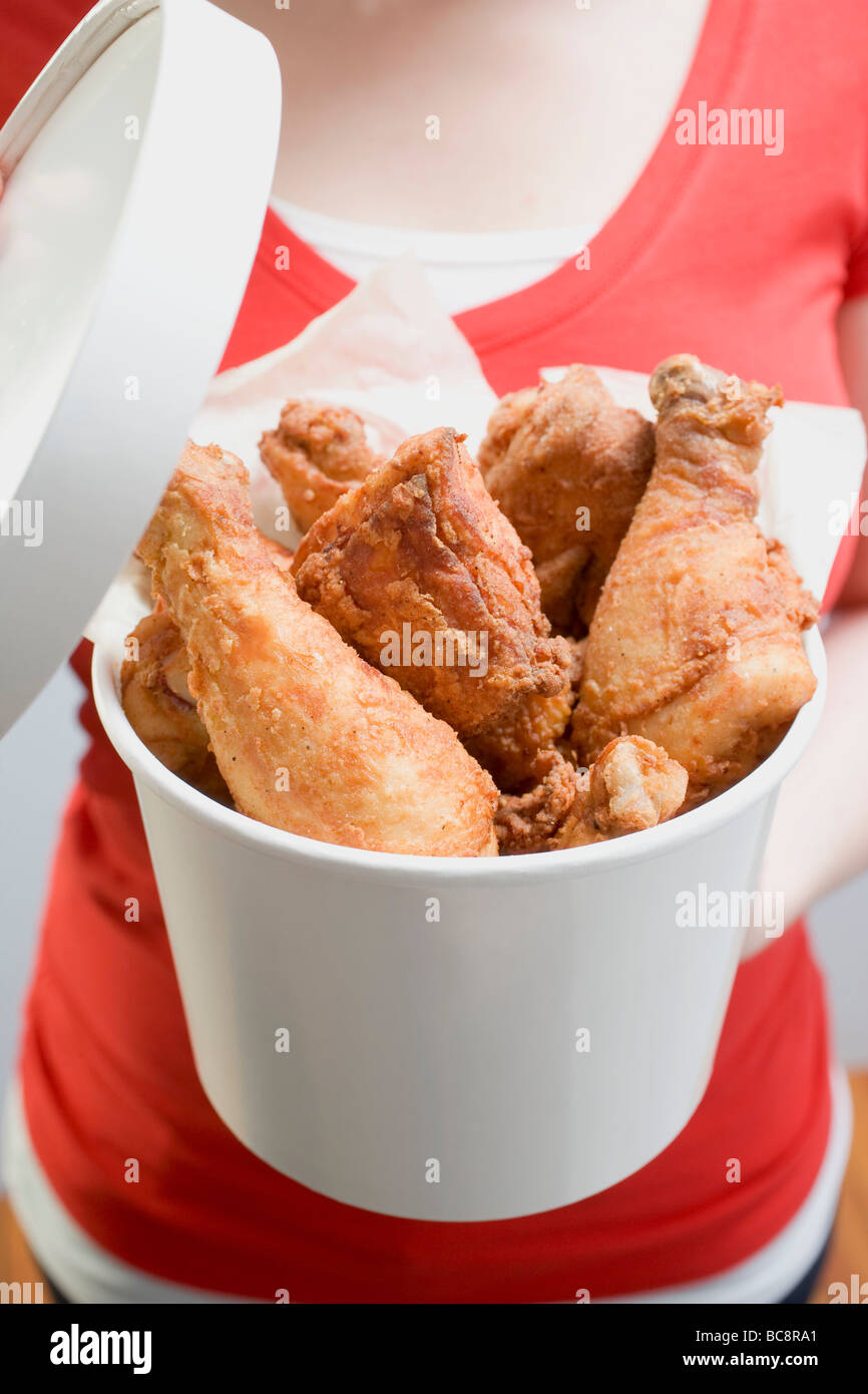 Woman holding bucket of deep-fried chicken drumsticks - Stock Photo