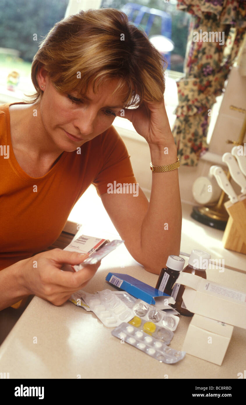 woman in her kitchen with a mixture of drugs deciding what to take Stock Photo