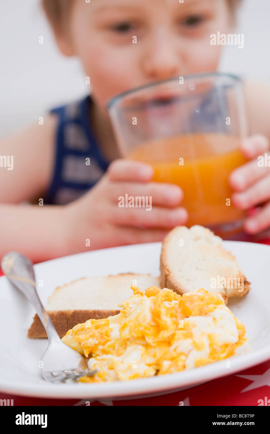 Scrambled egg & toast, little boy in background drinking juice Stock