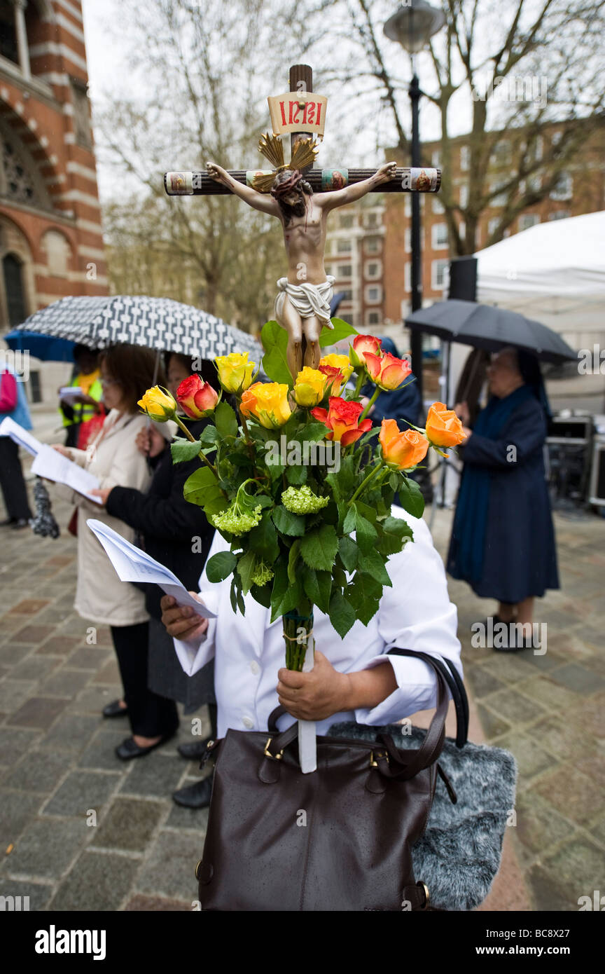 woman carrying a bunch of roses and an effigy of Christ Stock Photo
