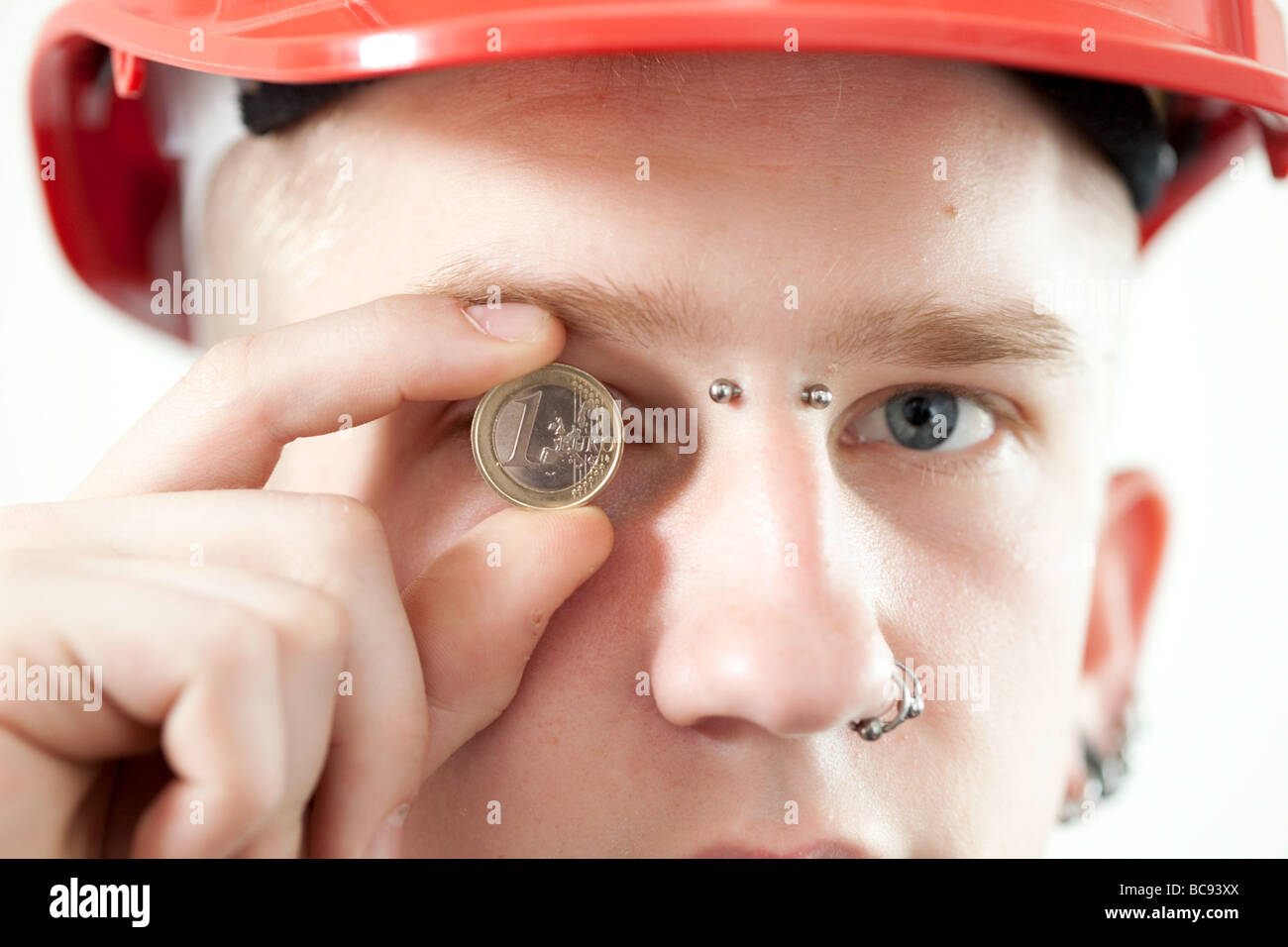Trainee wearing safty hat and holding an euro coin Stock Photo