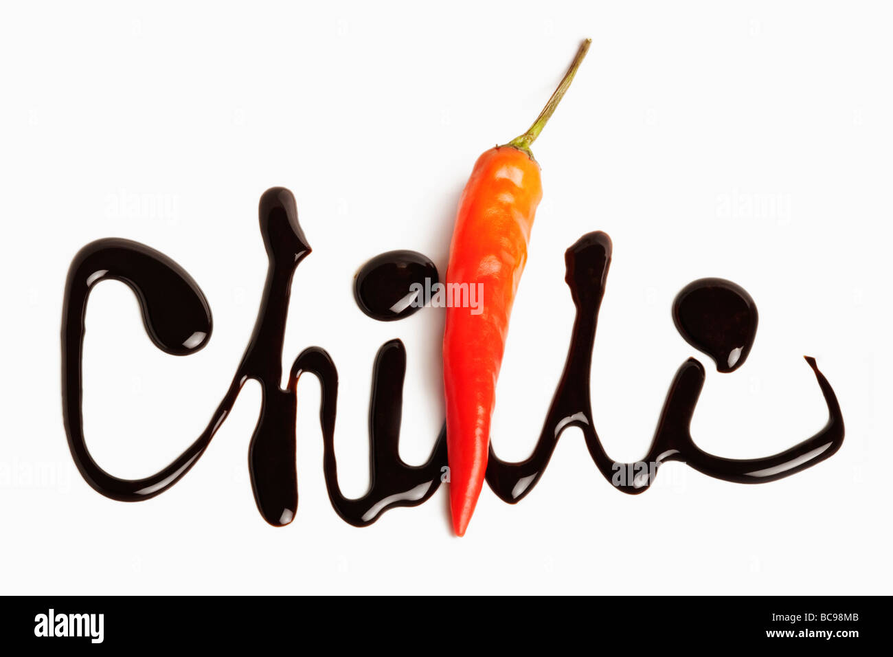 The word chilli written in chocolate Red chilli used as part of the word Against white background Stock Photo