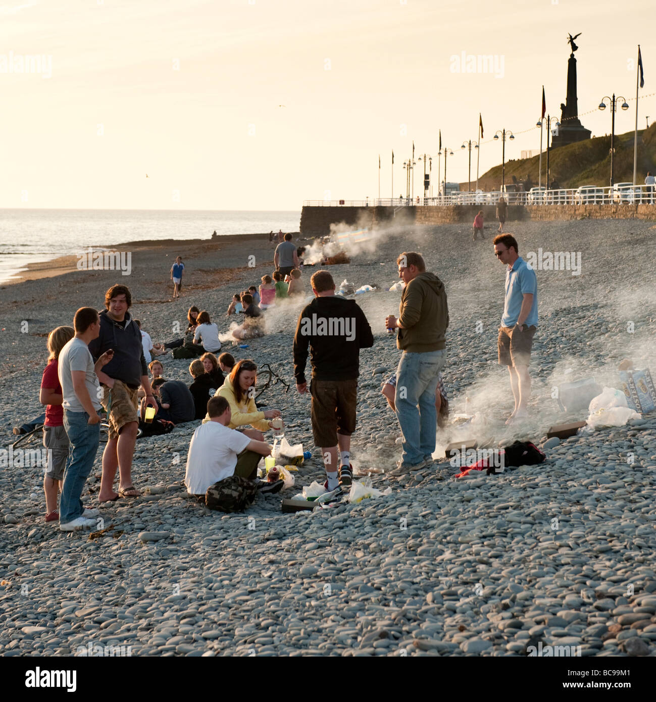Summer evening - groups of young students people having a barbecue on the beach Aberystwyth wales UK Stock Photo