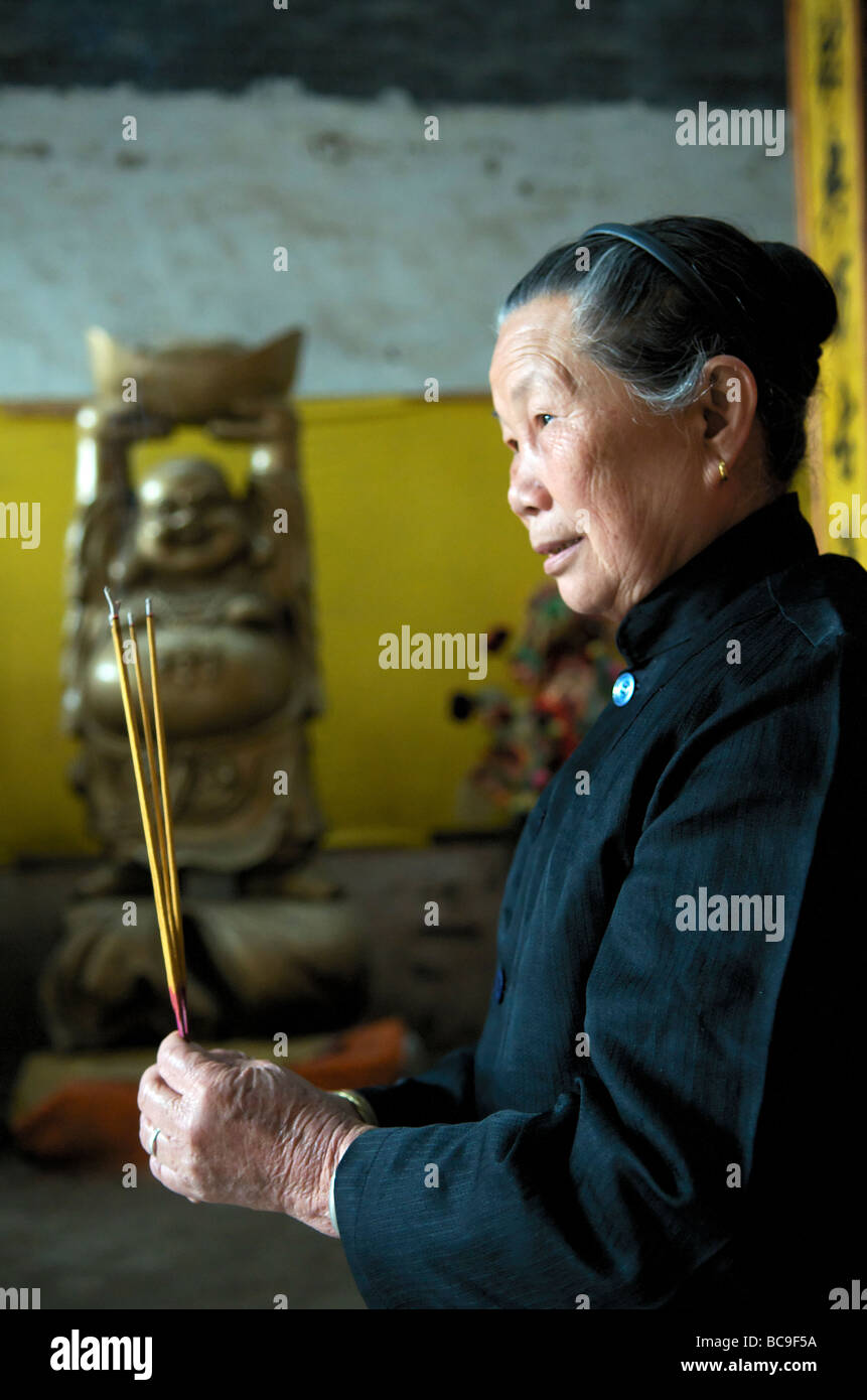 Portrait woman holding incense sticks in a temple Fuli Village near Yangshuo Guangxi China Stock Photo