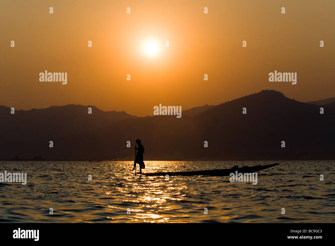 Silhouette of a rowing fisherman on Inle-Lake in Myanmar in the evening ...