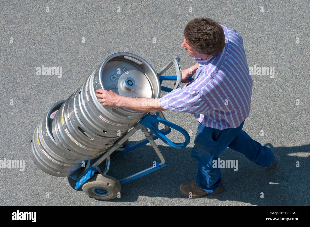 Beer delivery driver with metal kegs on 2wheeled truck France Stock