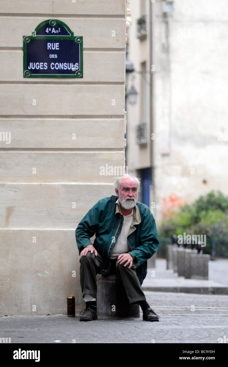 A drunk homeless man sitting down in a Paris street, France Stock Photo