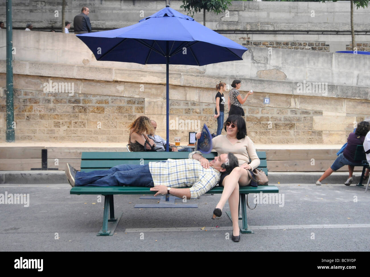 Parisian couple relaxing on a public bench during the annual Paris Plage summer event in Paris, France. Stock Photo