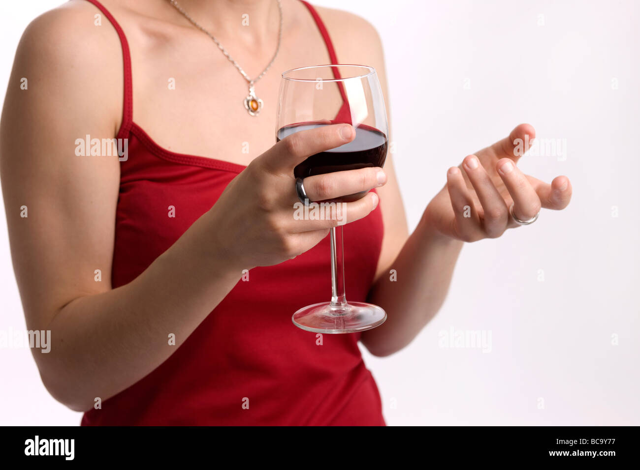 Close up of a well-dressed young woman talking whilst holding a drink Stock Photo