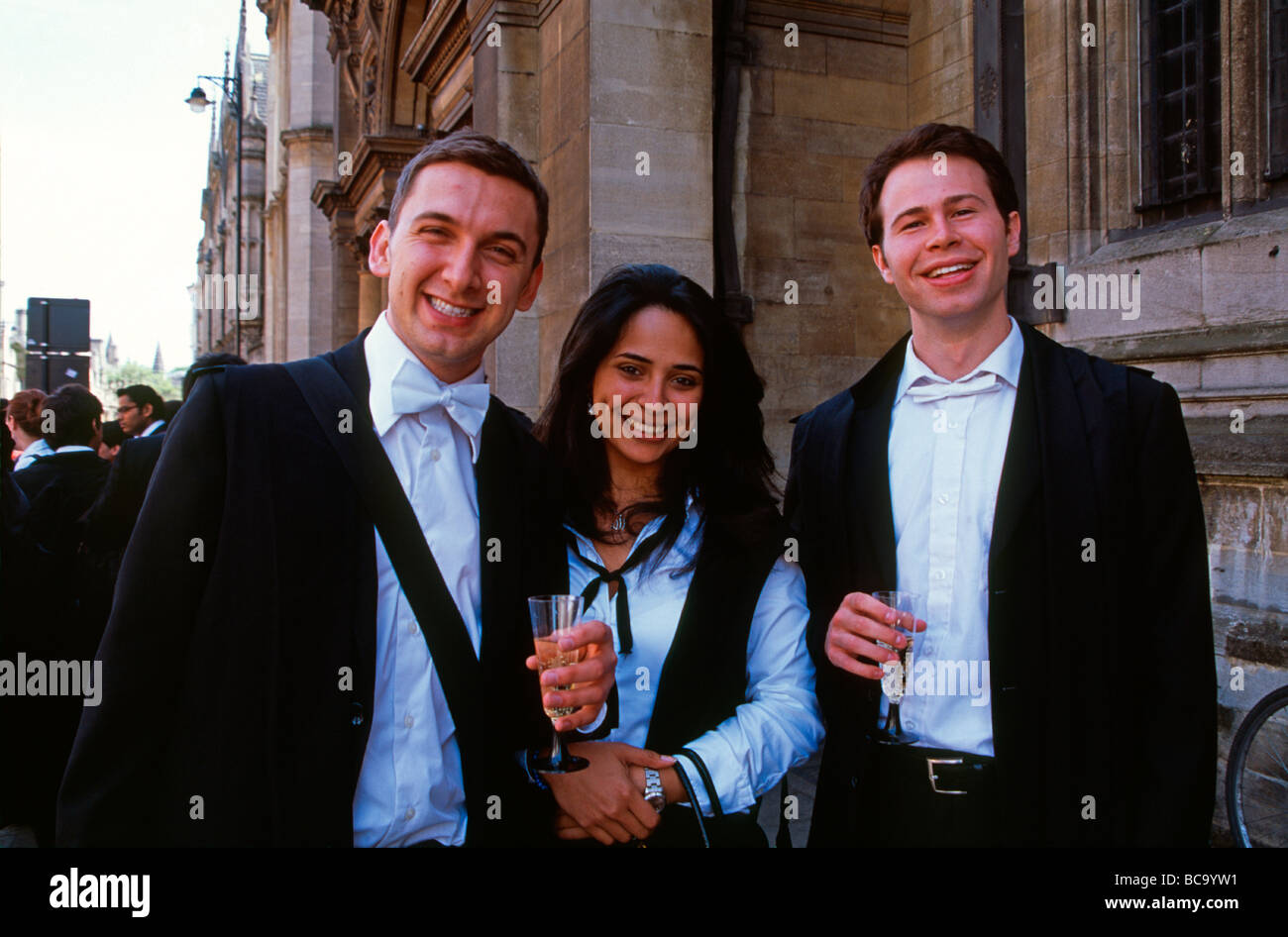 Oxford University Students in subfusc (traditional garb) drinking champagne outside University College after finals England UK Stock Photo