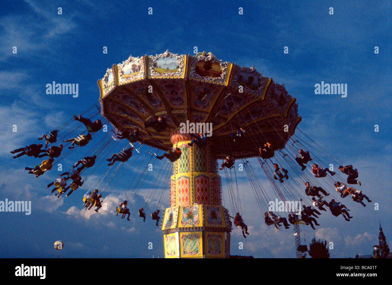 Funfair with people swinging out from rotating carousel Stock Photo