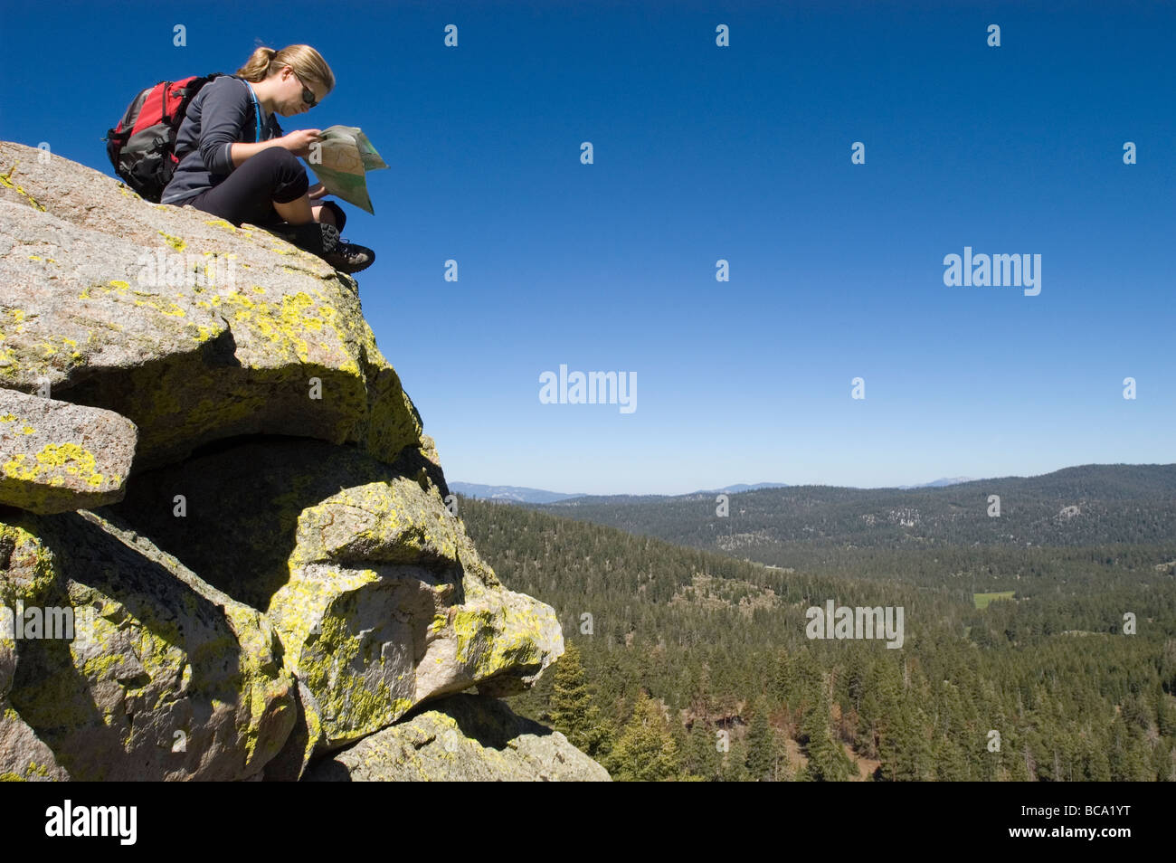 A female hiker reads a map from atop Jackass Peak (9,287 feet). Stock Photo