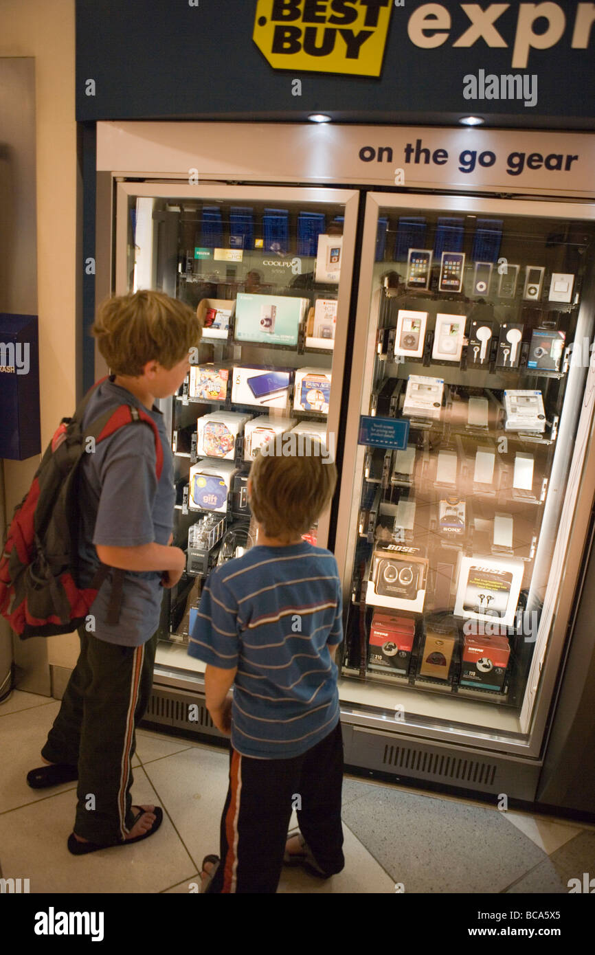 two children looking at electronics vending machine at airport, containing video games, movies, computer software Stock Photo