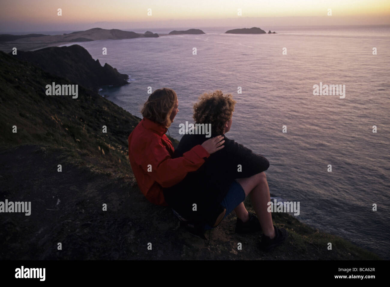 Couple watching sunset at Cape Reinga, northernmost point of New Zealand, North Island, New Zealand Stock Photo