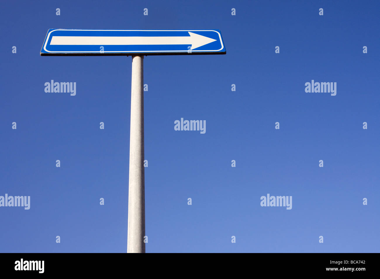 A blue arrow sign pointing right with a blue sky Stock Photo