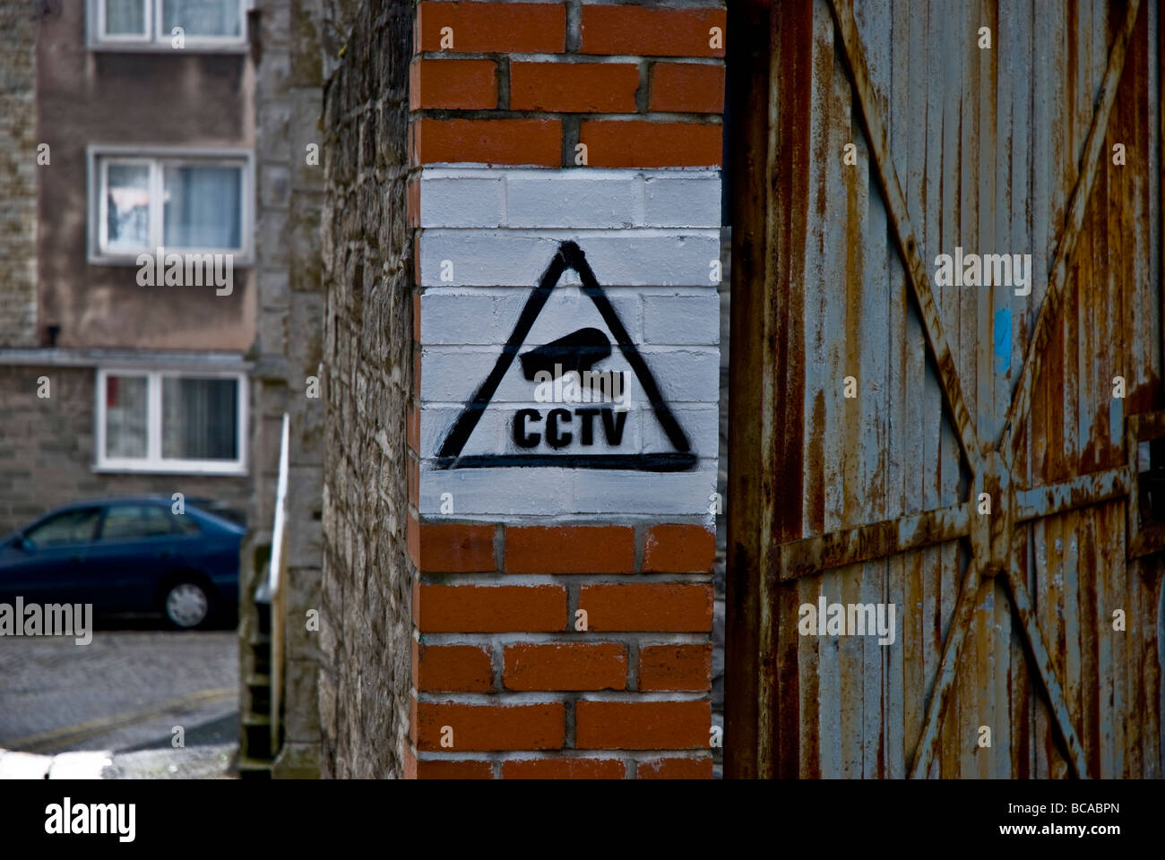 A home-made CCTV sign in white and black paint on a brick wall. Stock Photo