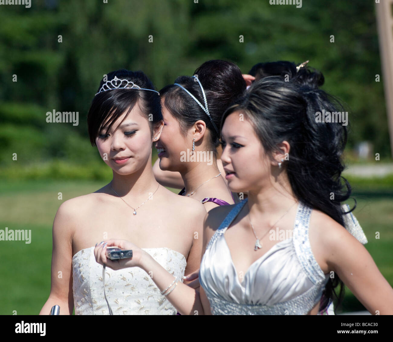girl students in formal dress for school prom posing for photographs at Queen Elizabeth Park, Vancouver, British Columbia, Canad Stock Photo