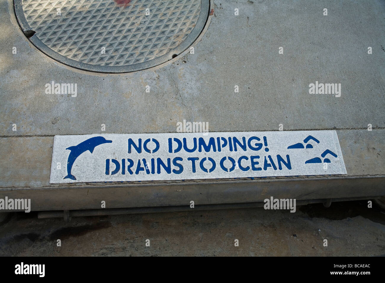Painted sign on curb warns about dumping into drain Stock Photo