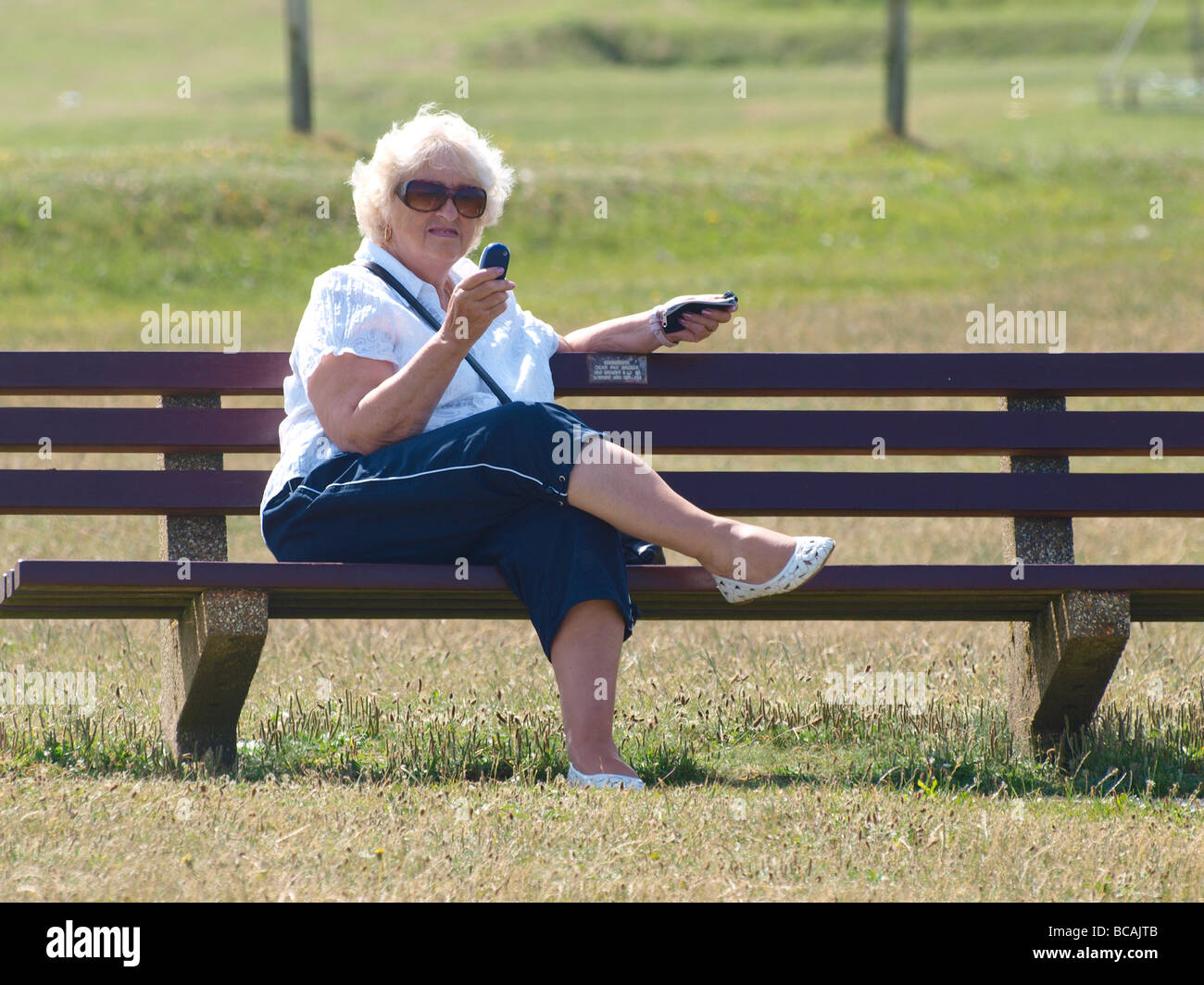 Old Woman Sat On Park Bench Texting Stock Photo Alamy