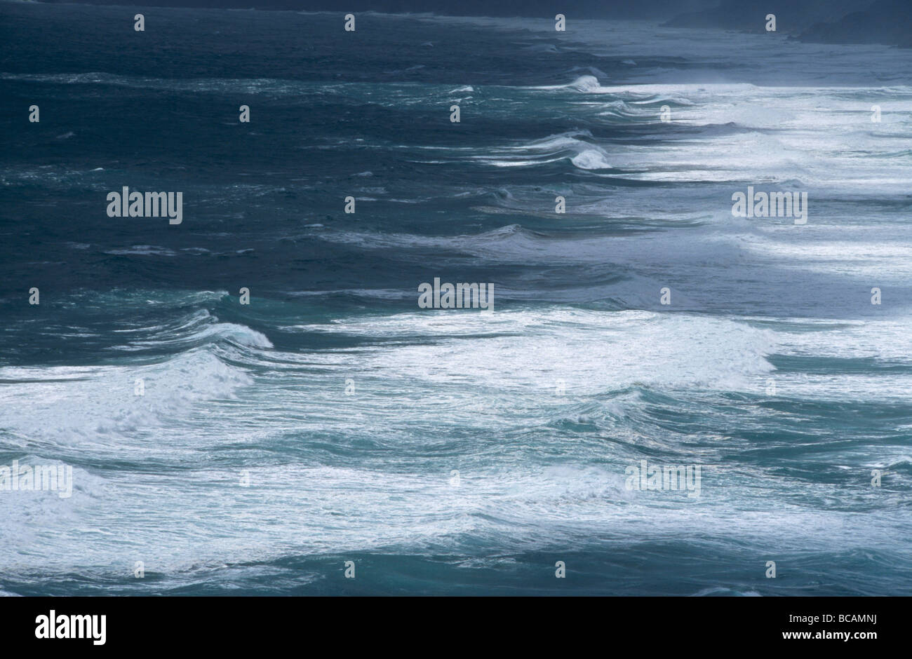 Choppy seas and crashing waves pound a rugged treacherous coastline. Stock Photo