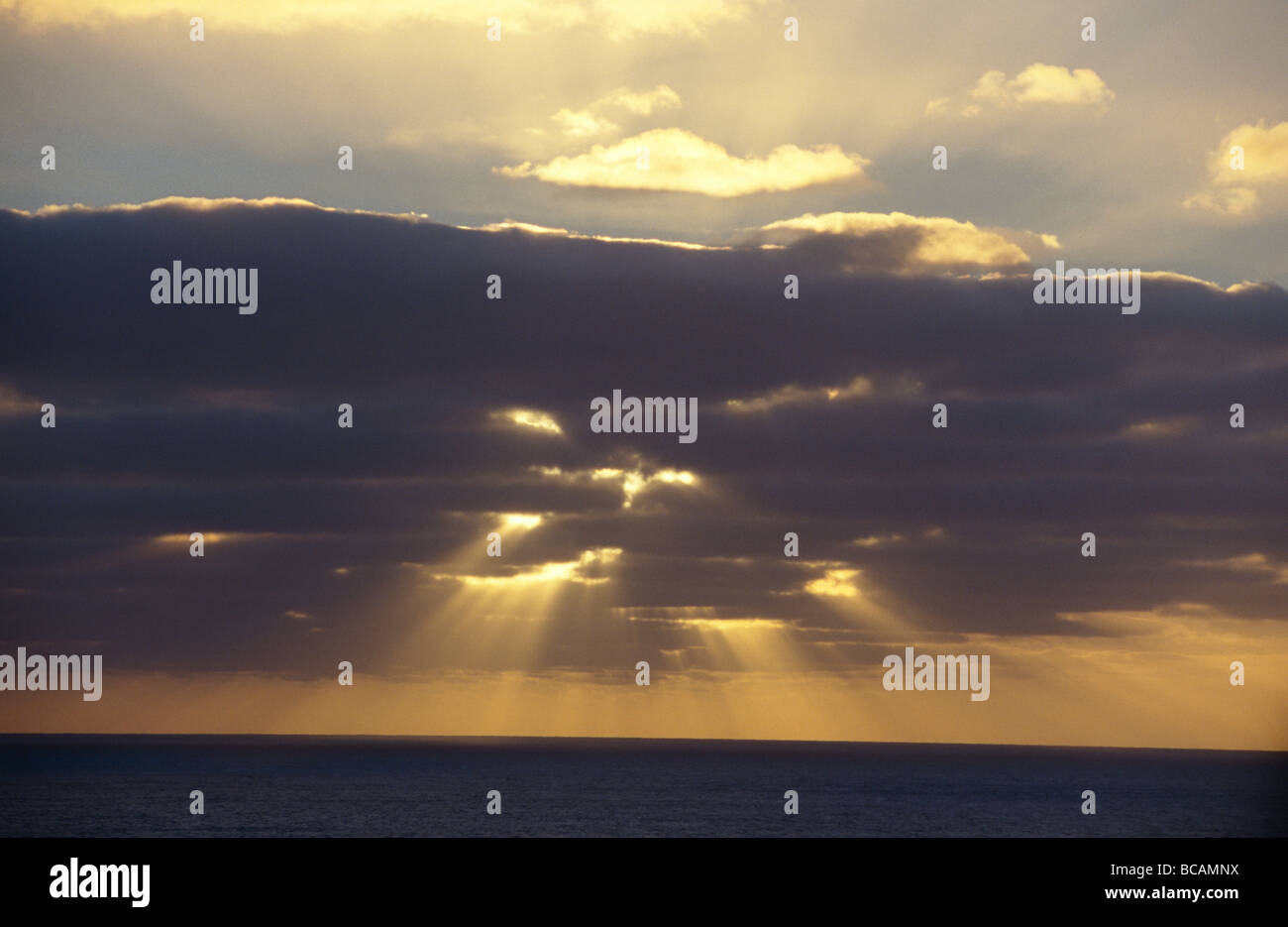 Sun rays pierce storm clouds over a vast calm ocean Stock Photo - Alamy