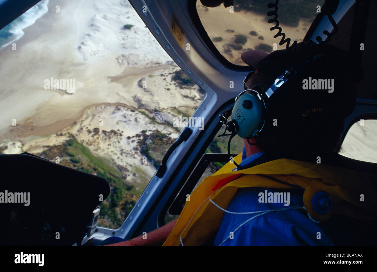 A Helicopter Pilot flying sharply over remote coastal plains. Stock Photo