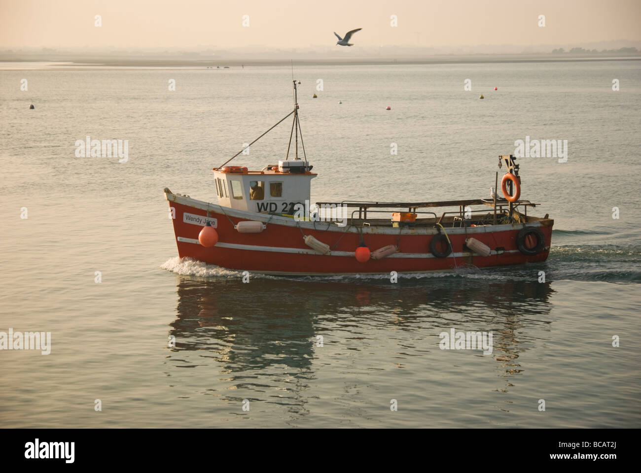 Red fishing boat sailing in Howth harbour, Ireland Stock Photo