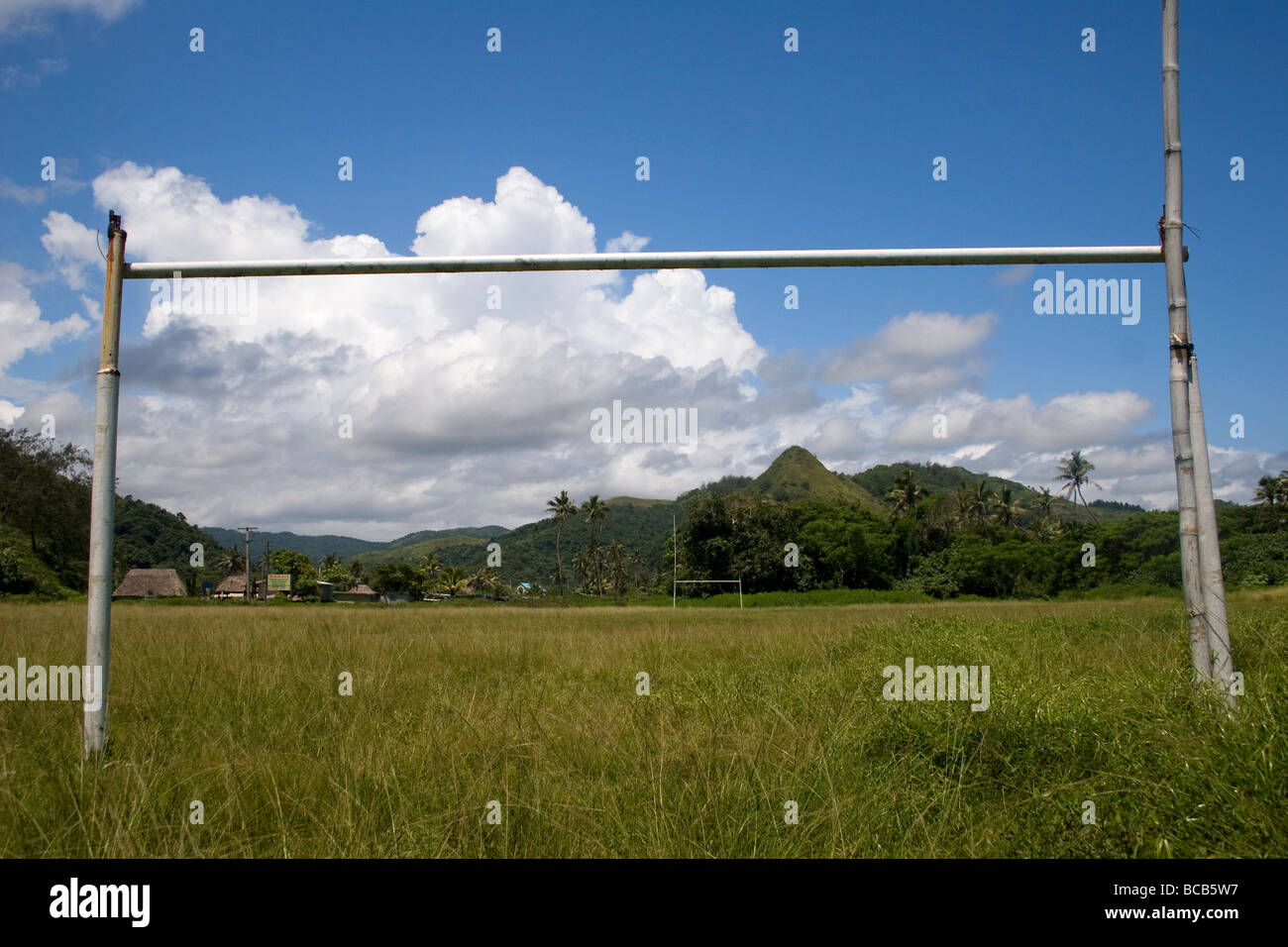 a Broken makeshift rugby post is visible in the Fijian landscape with overgrown grass on a rugby field Stock Photo