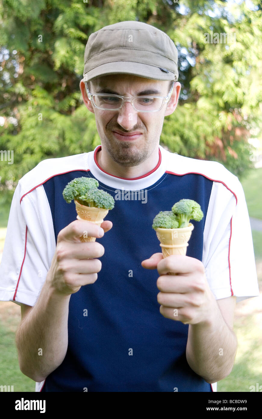 Young Man Making Face While Holding Ice Cream Cones Filled With Broccoli Stock Photo Alamy