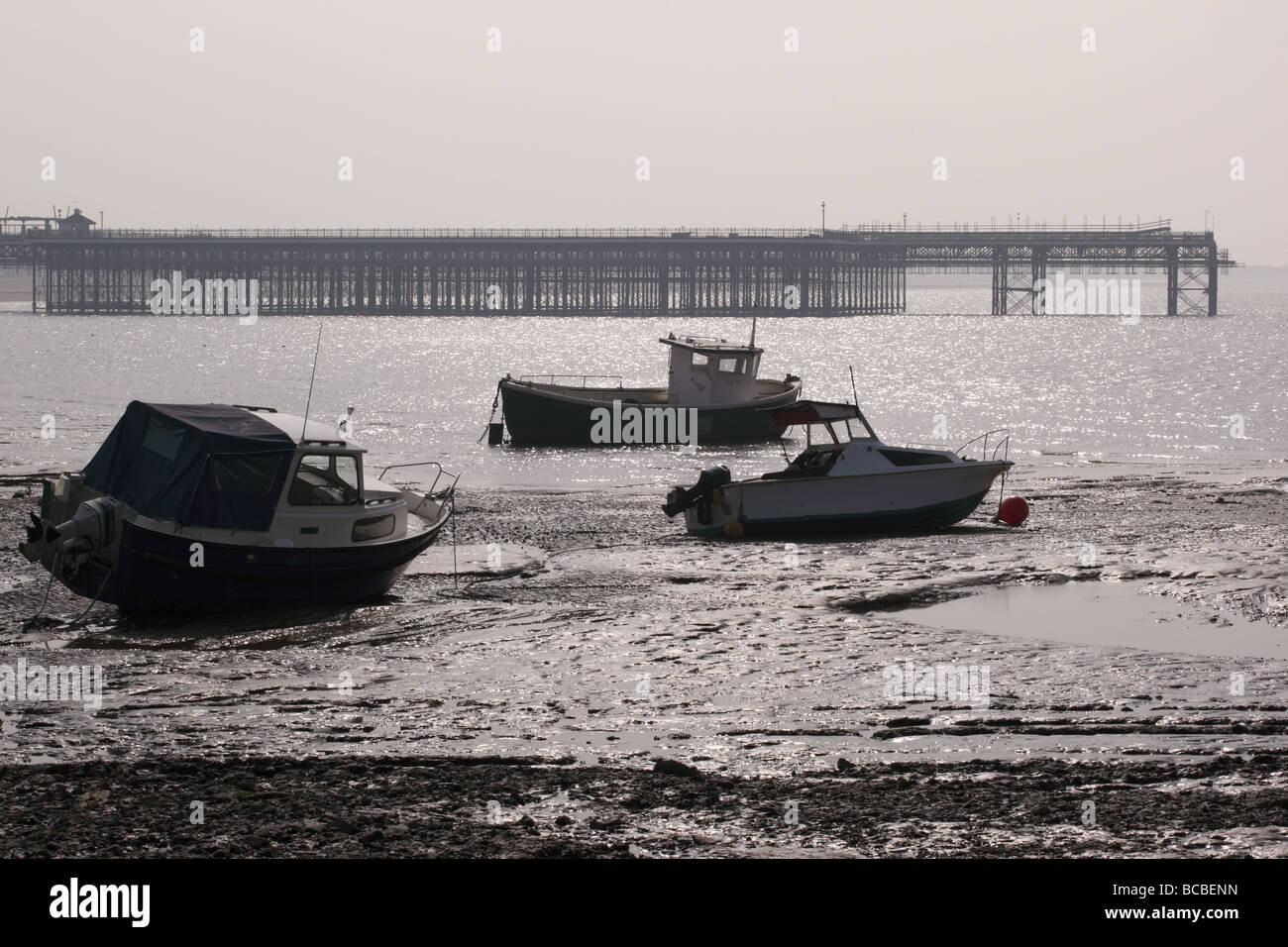 Ruined pier at Weston Super Mare with marooned boats in foreground, England Stock Photo