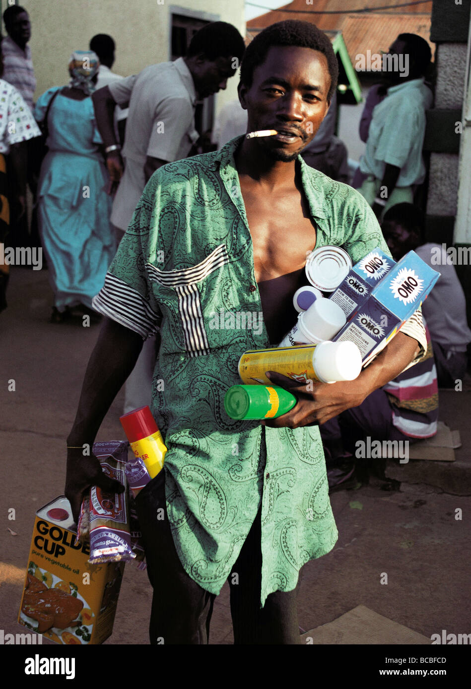 Male black Africa man customer laden with purchases leaving Nakasero Market Kampala Uganda East Africa with cigarette Stock Photo