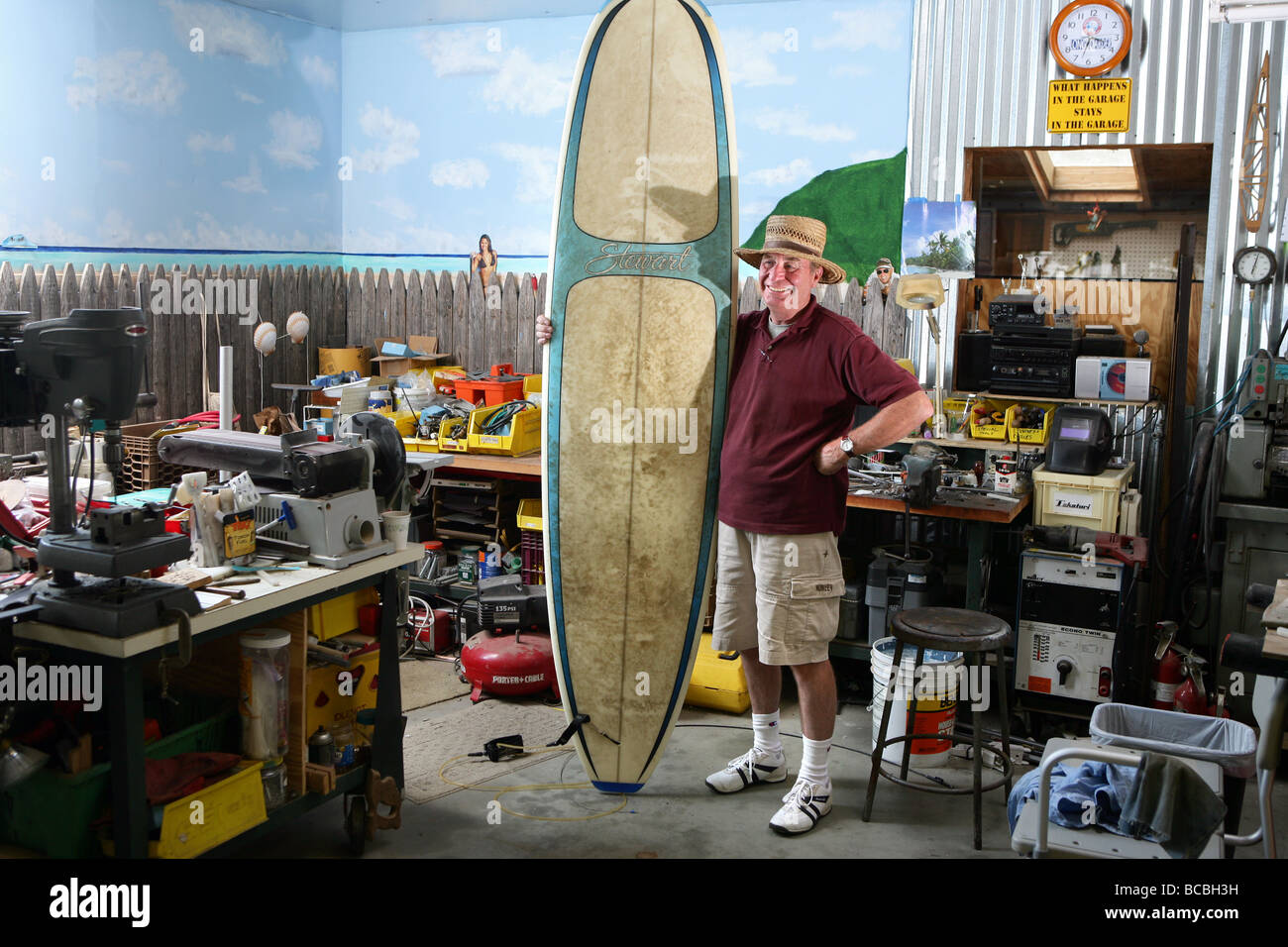 Baby Boomer man with surfboard in garage Stock Photo