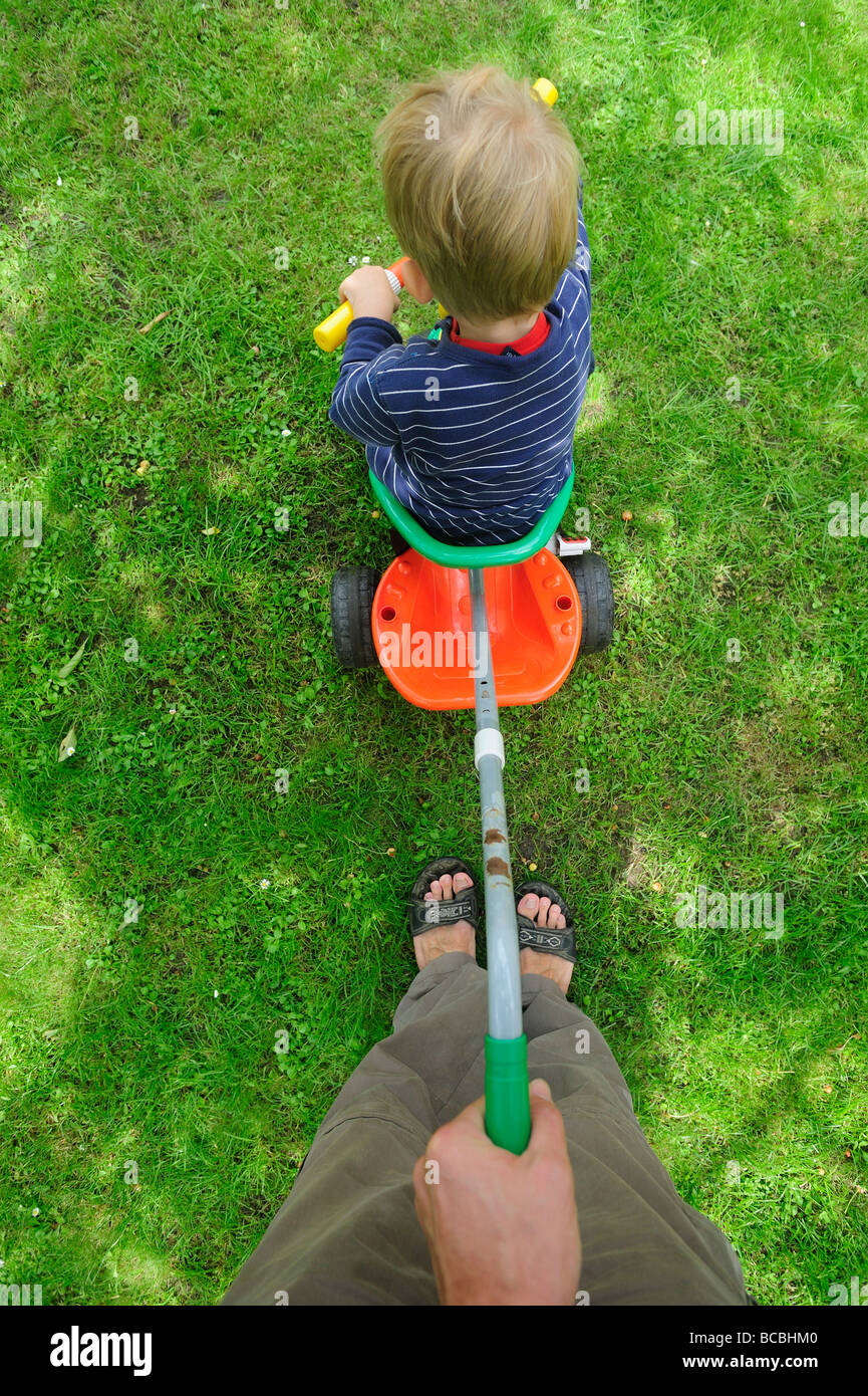 Three year old blond boy riding tricycle with father Stock Photo Alamy
