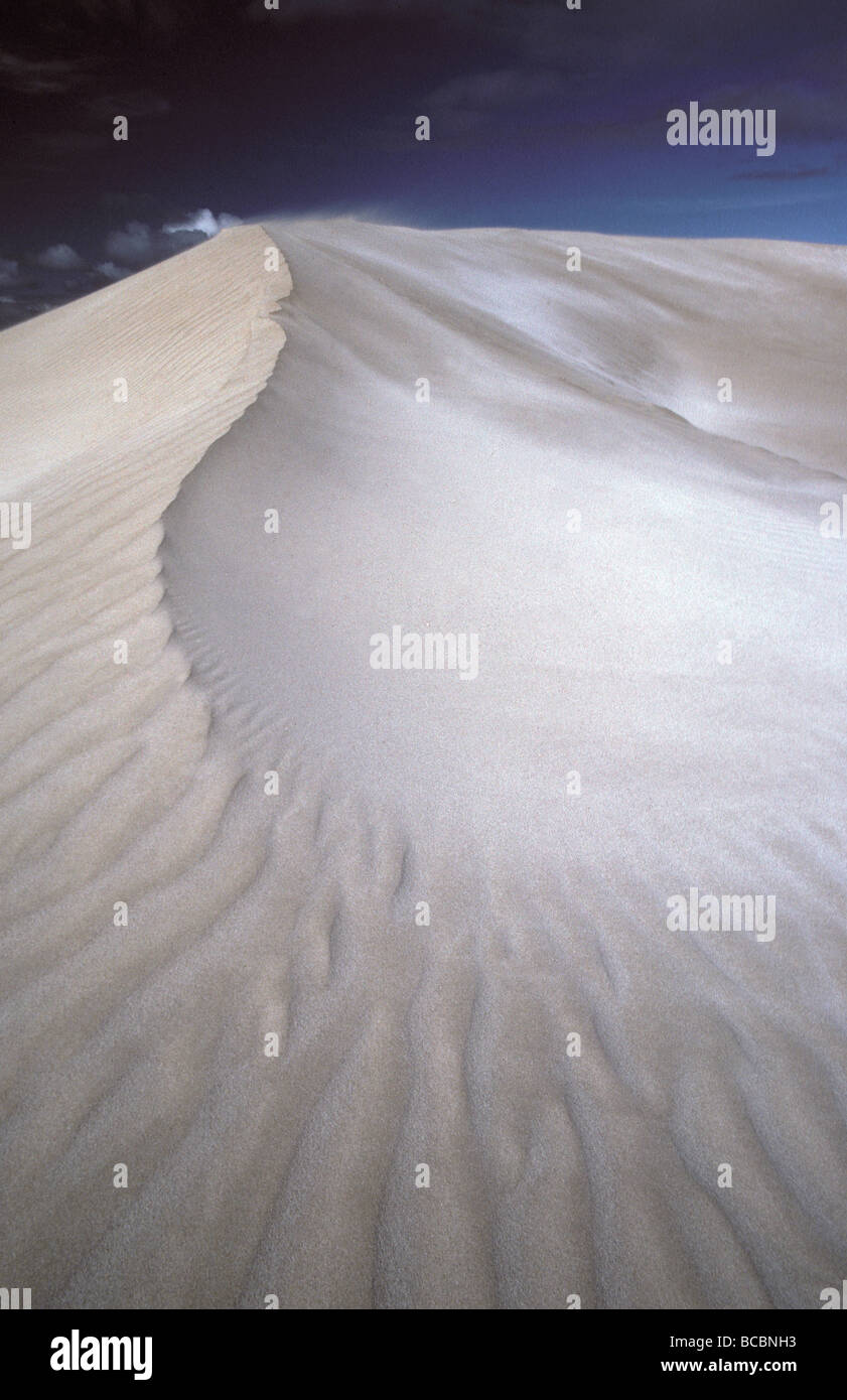 A vast coastal, white gleaming sand dune against a hazy blue sky. Stock Photo