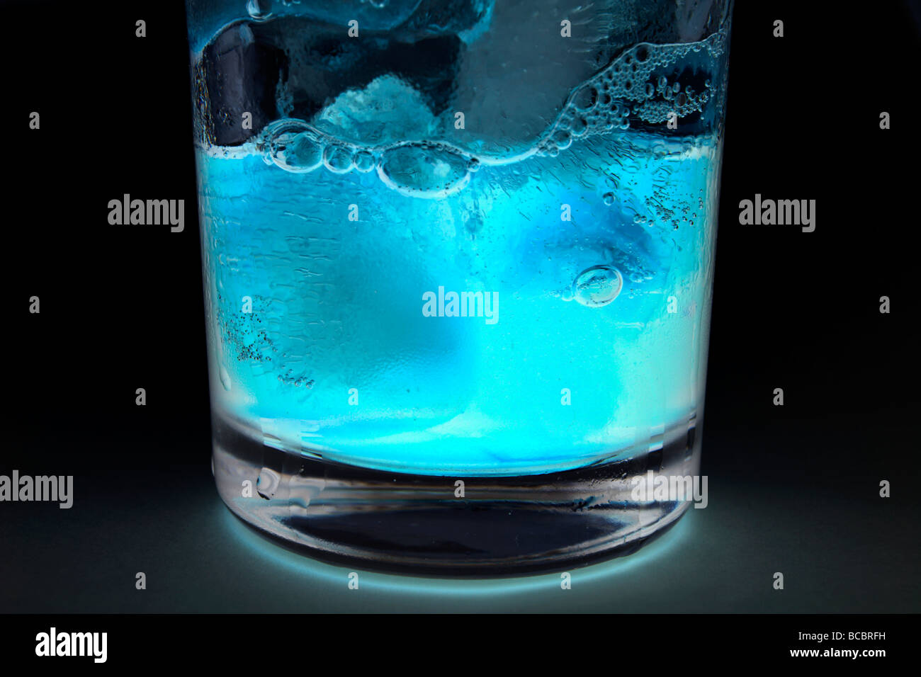 A glass containing blue coloured liquid and ice cubes Stock Photo
