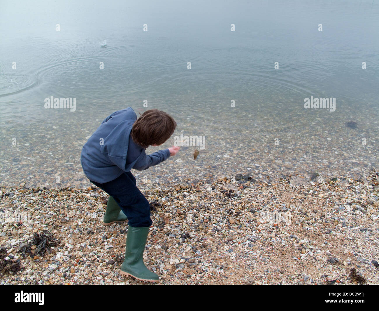 Little boy skimming stones in Lulworth Cove Stock Photo
